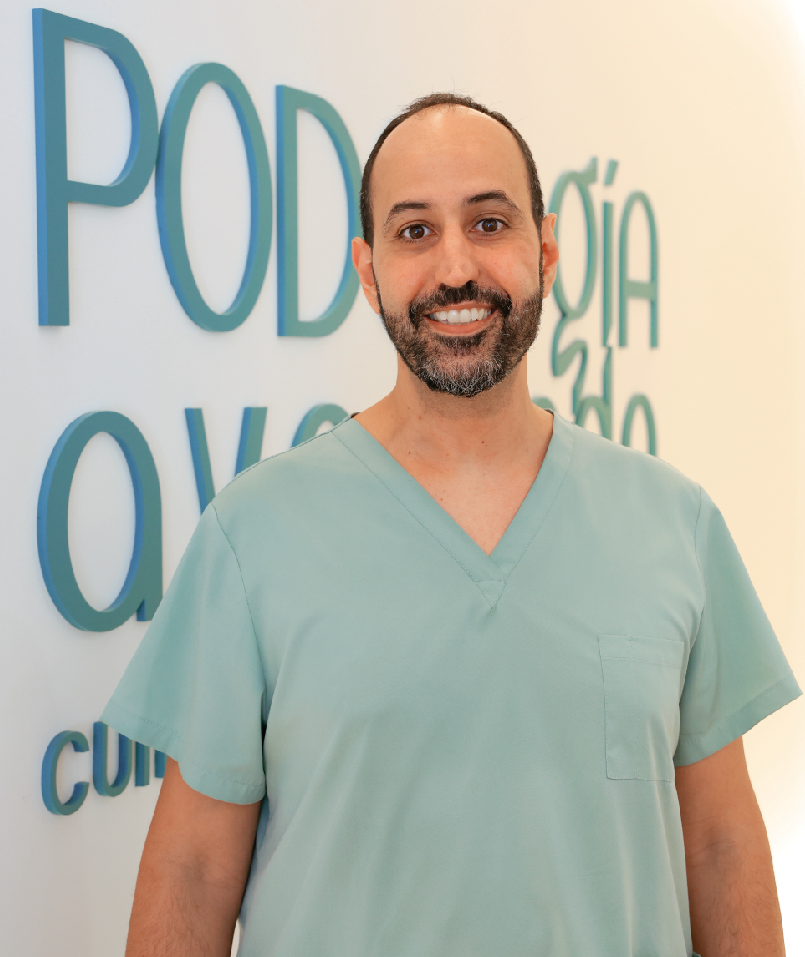 Hombre con barba y camiseta verde Podólogo profesional de Podología Avanzada Palma con bata verde claro